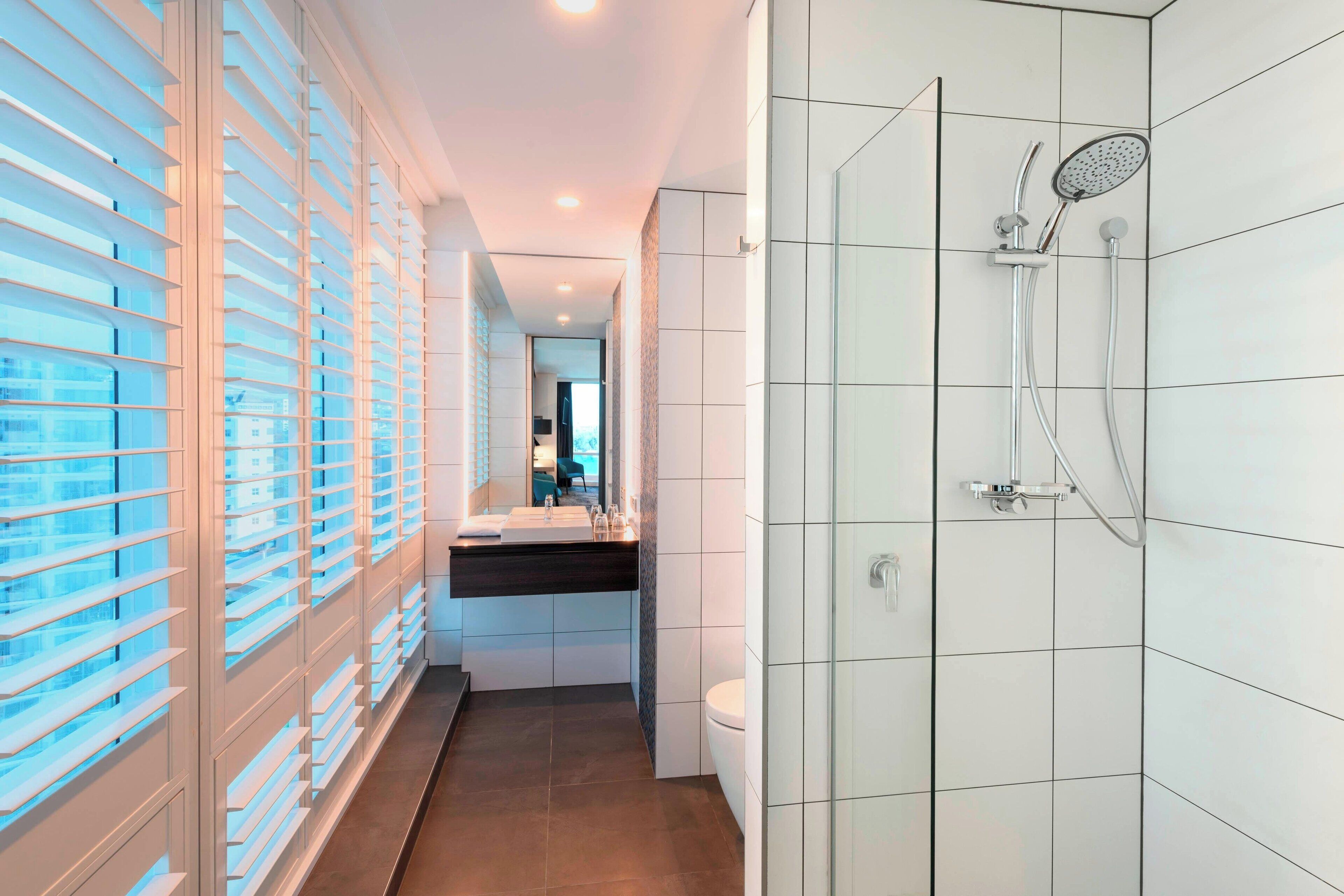 A modern bathroom with a shower, toilet, and sink.