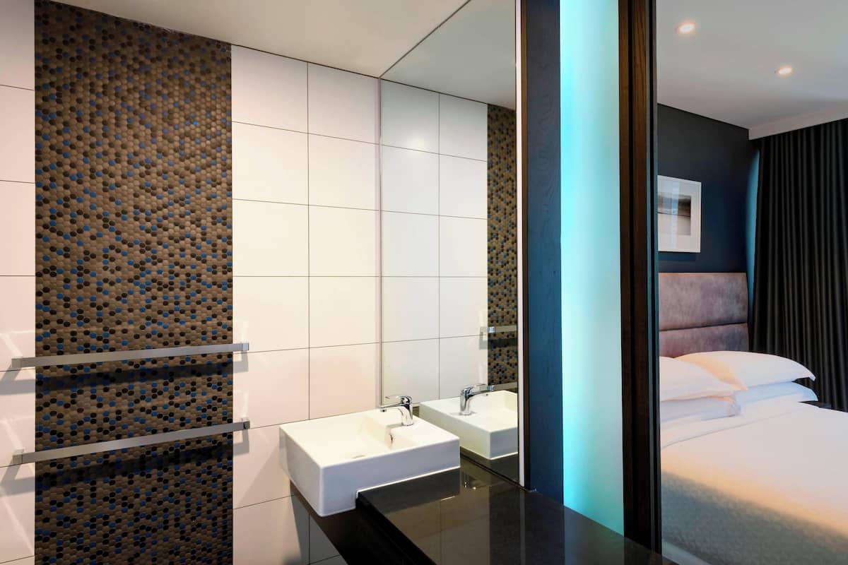 A modern bathroom with a large mirror, two sinks, and a black countertop.
