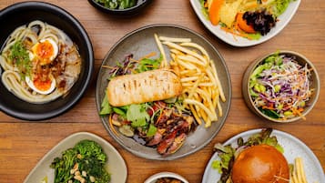 Un assortiment de plats comprenant un bol de nouilles, un sandwich, des frites et des salades.