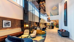 A spacious lobby with a high ceiling, modern seating arrangements, and a large staircase. - Four Points by Sheraton Auckland (Auckland)