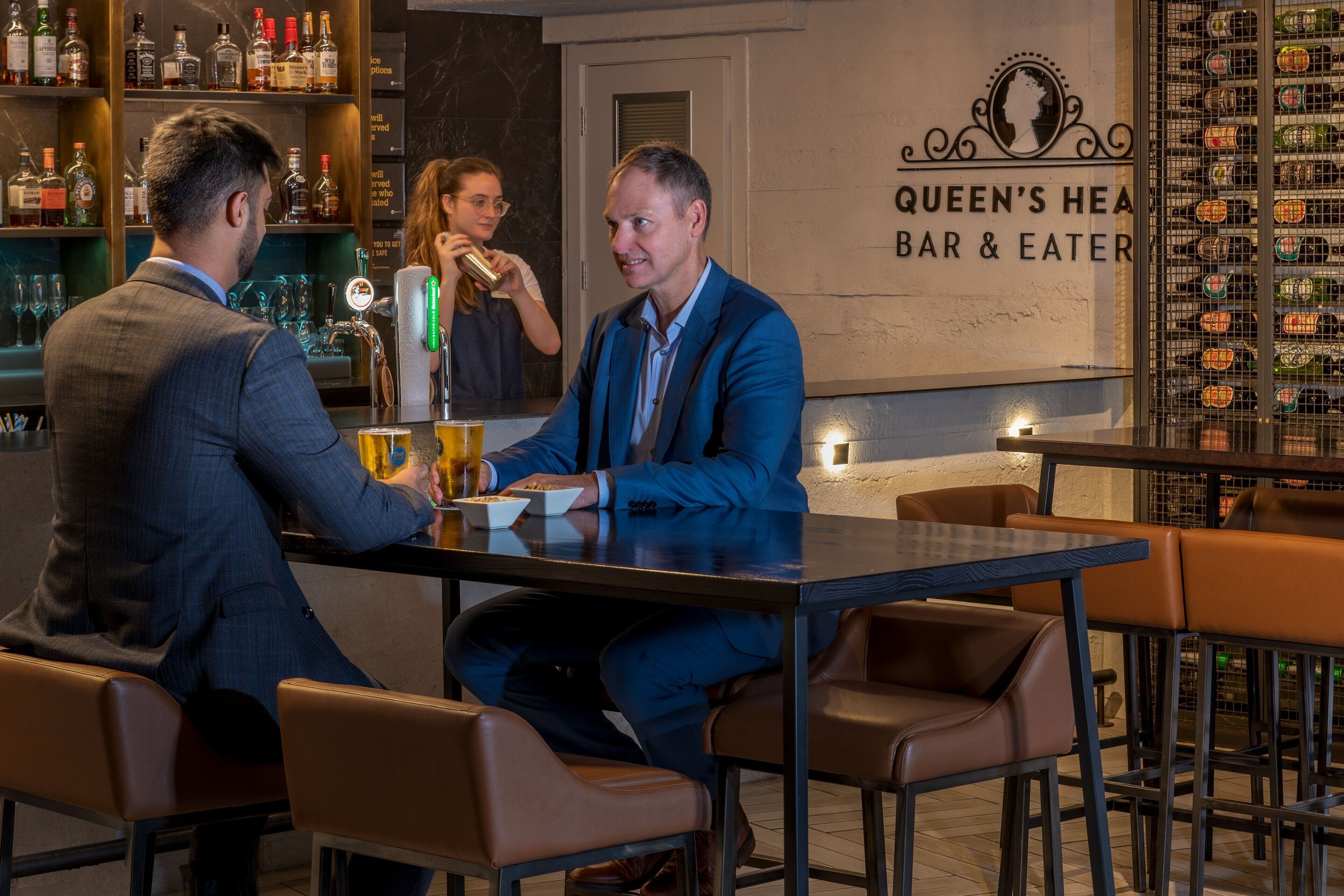 Uma área de bar com uma placa indicando 'Queen's Head Bar & Eater'.
