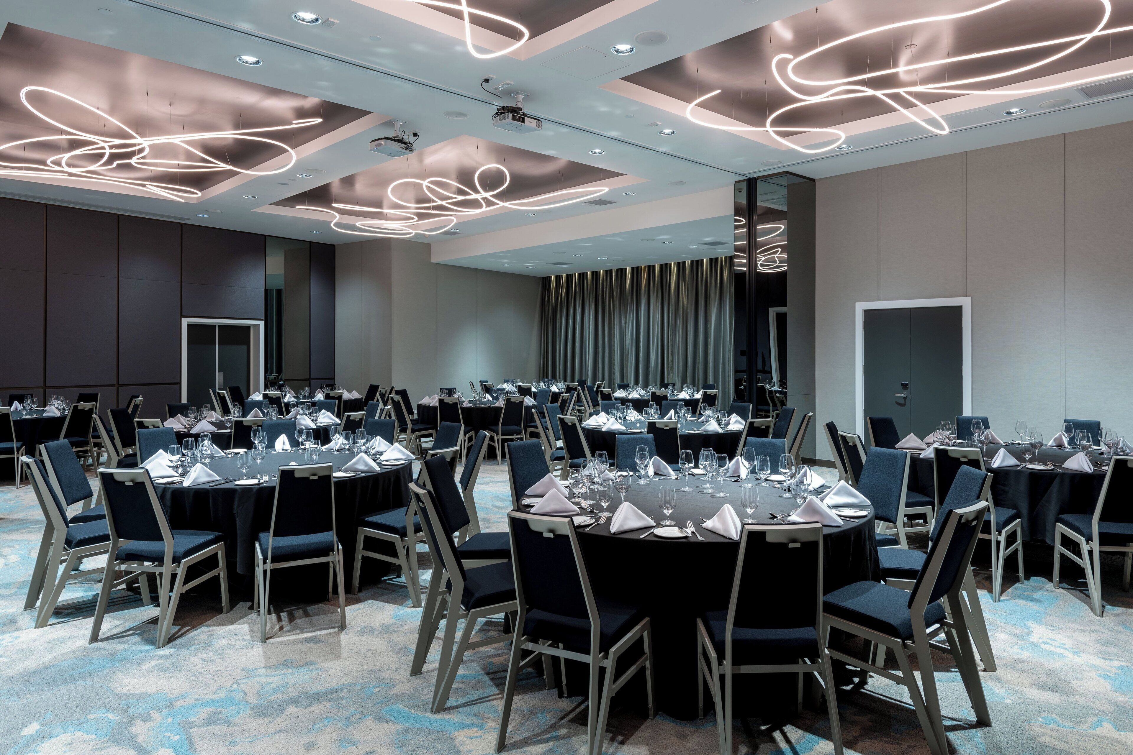 A conference room with round tables, chairs, and a modern ceiling design.