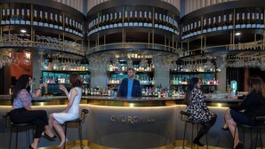 A bar area with a circular design, bar stools, and a bartender. - Four Points by Sheraton Auckland (Auckland)
