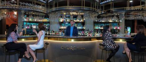 A bar area with a circular design, bar stools, and a bartender.