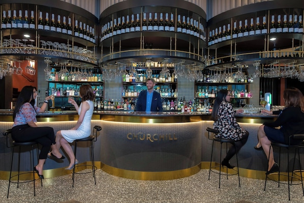 A bar area with a circular design, bar stools, and a bartender.