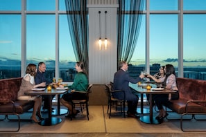 A group of people dining at a table with a city view, in a room with large windows and curtains. - Four Points by Sheraton Auckland (Auckland)