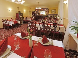 A dining area with multiple tables set for service, featuring red tablecloths and white plates. - Hotel Mignon (Karlovy Vary)
