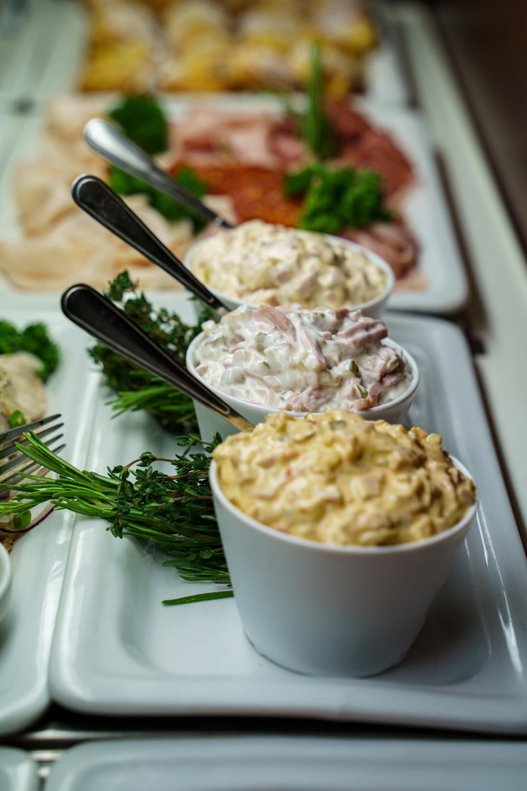 A tray with various dips and garnishes, including a creamy dip with herbs and a chunky dip with a golden-brown crust.