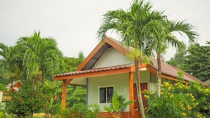 A bungalow with a tiled roof, surrounded by lush greenery and flowering plants. - Lanta Smile Beach At Klong Dao (Ko Lanta)