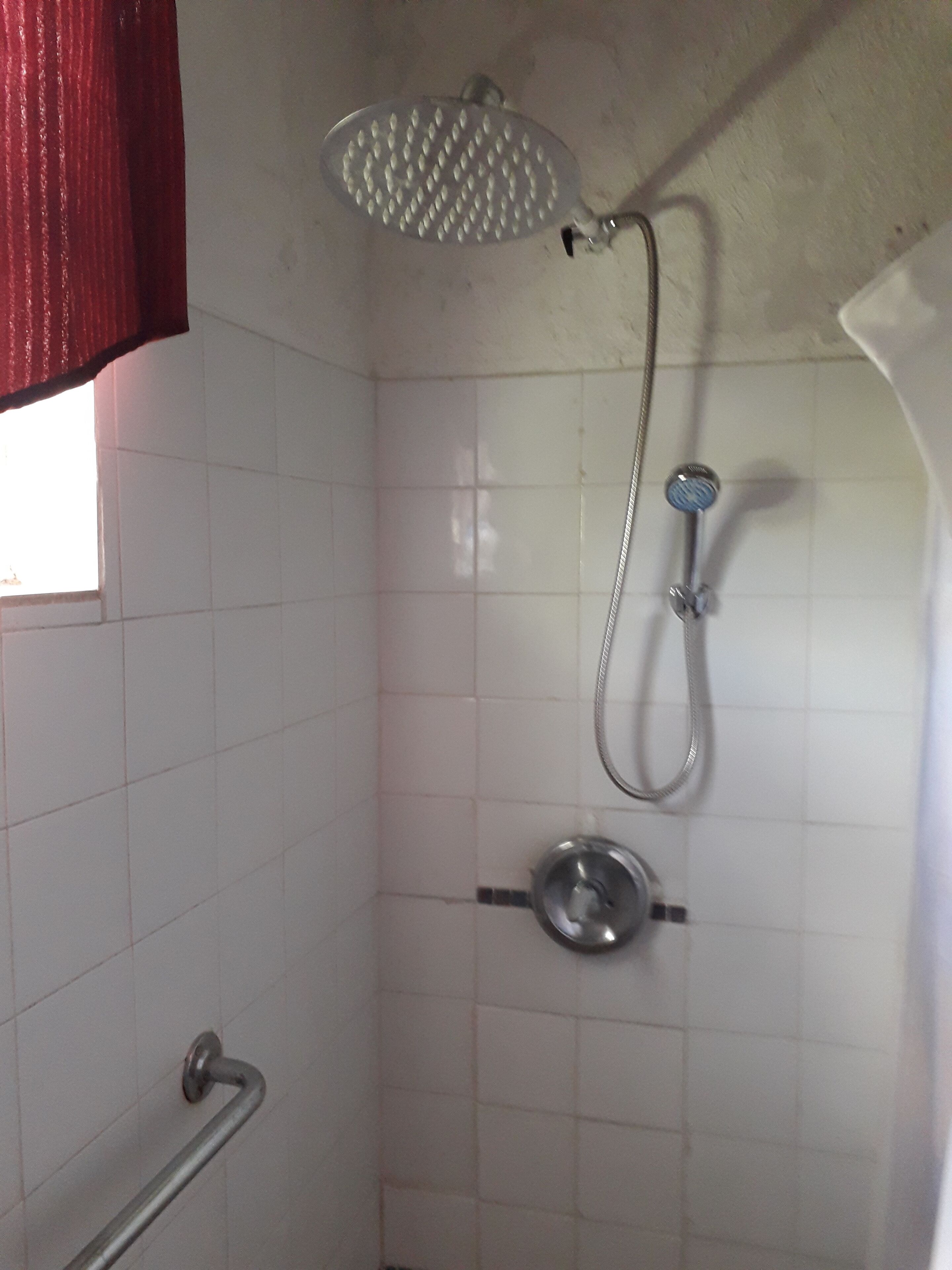 Ducha con cabezal de ducha y grifo de mano.