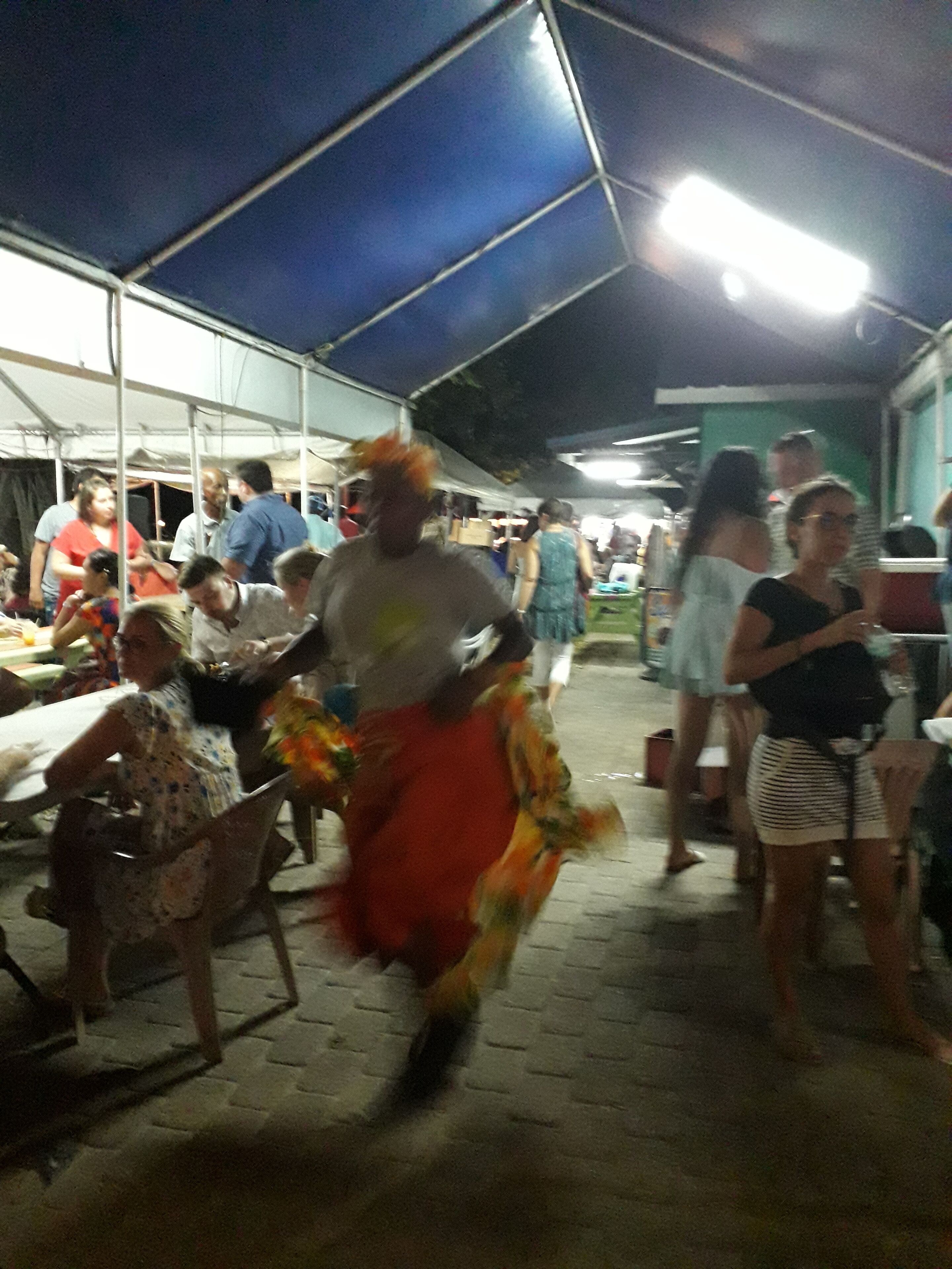 Evento ao ar livre com tendas, pessoas e mesas.