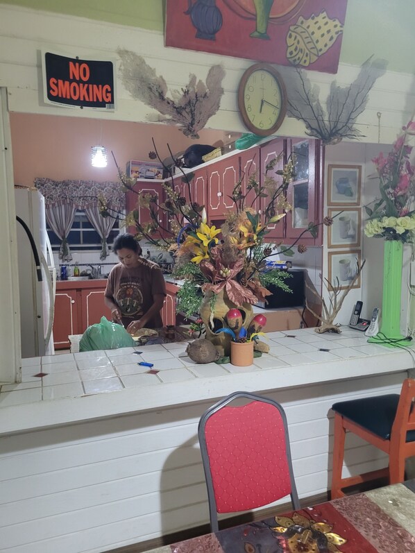 A kitchen area with a 'NO SMOKING' sign, a clock, and decorative plants.