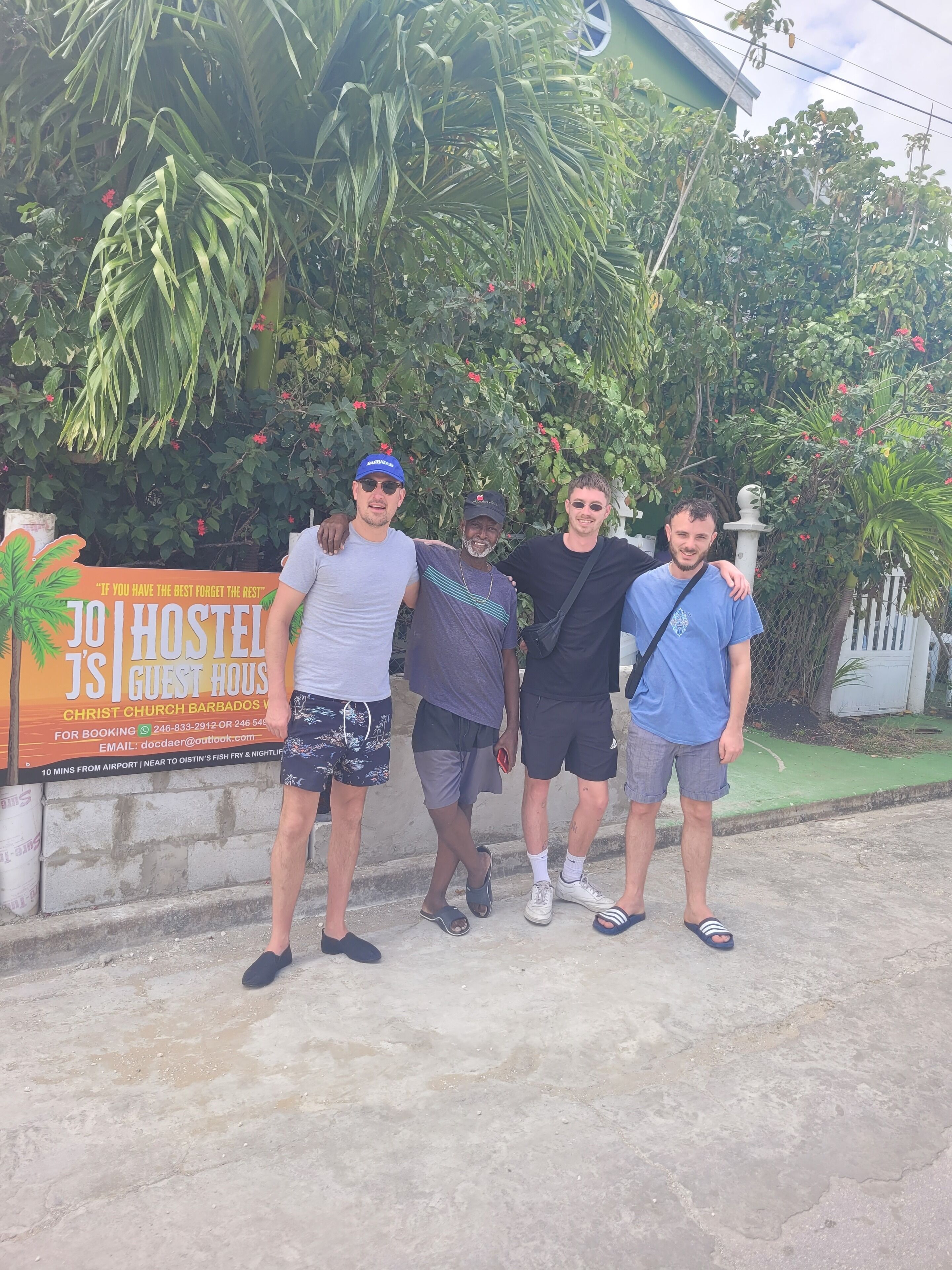 Four people standing in front of a sign for a hostel.