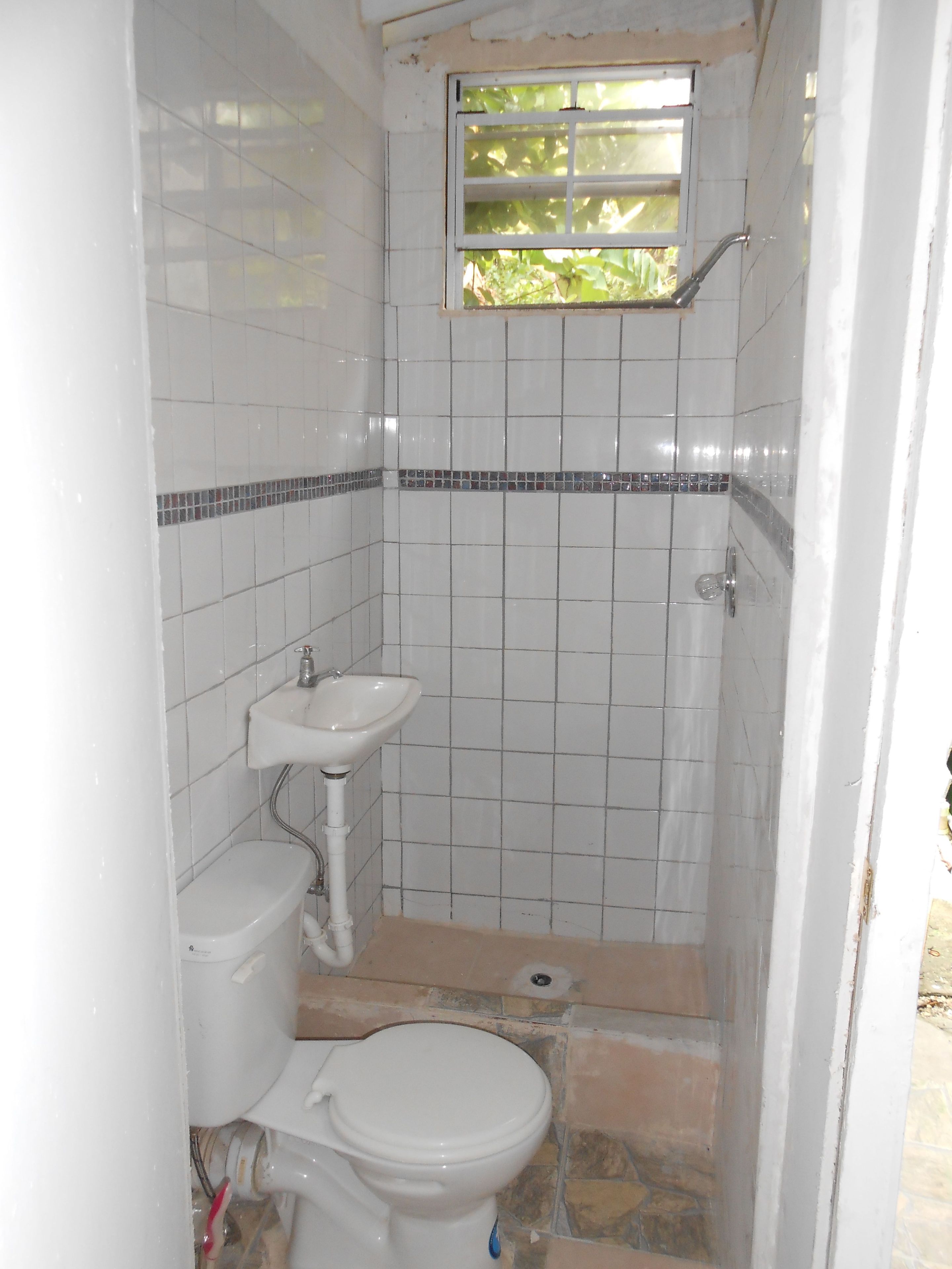 Un baño pequeño con azulejos, que incluye inodoro, lavabo y ducha.