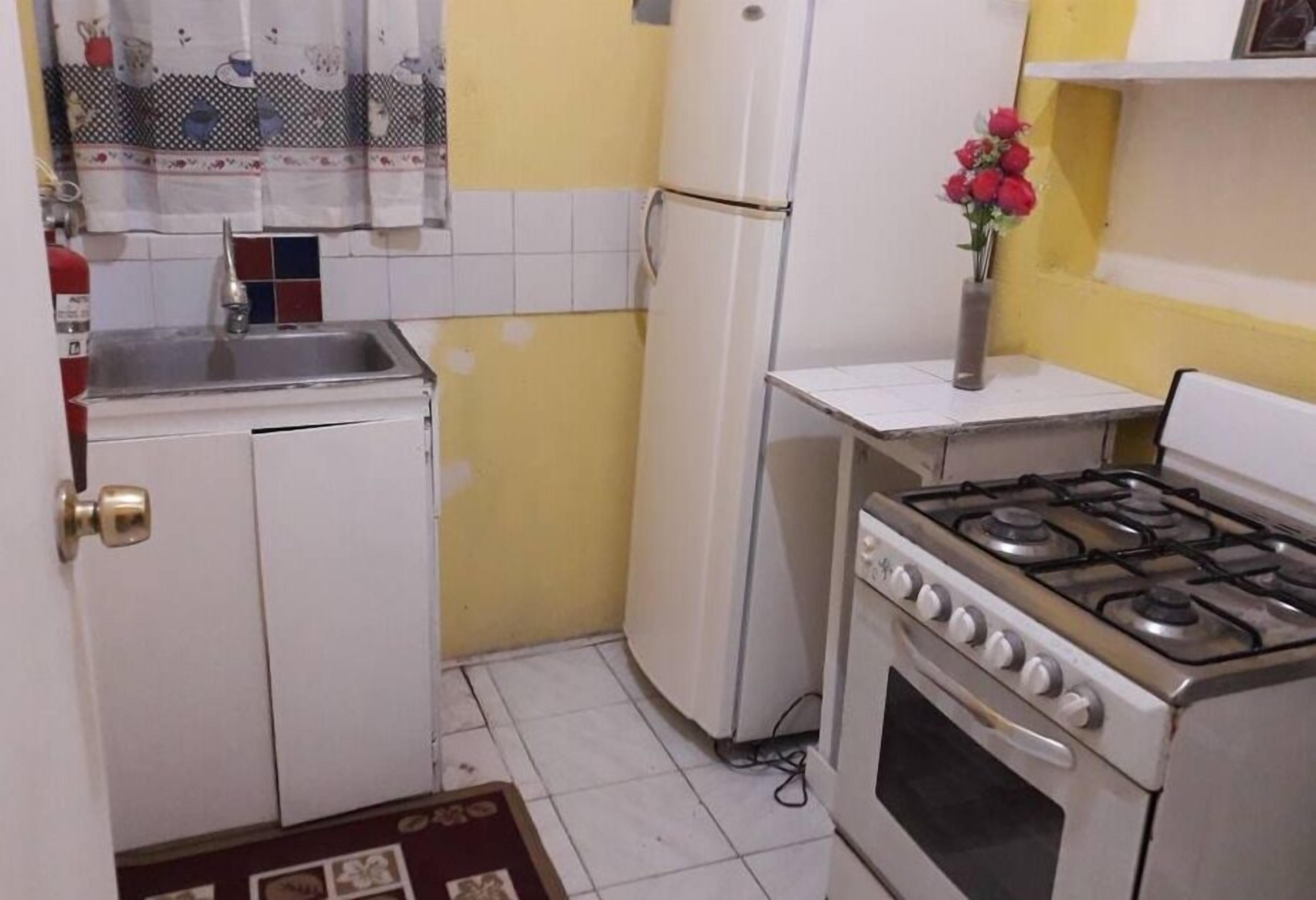 Una cocina compacta con refrigerador, estufa y lavamanos.
