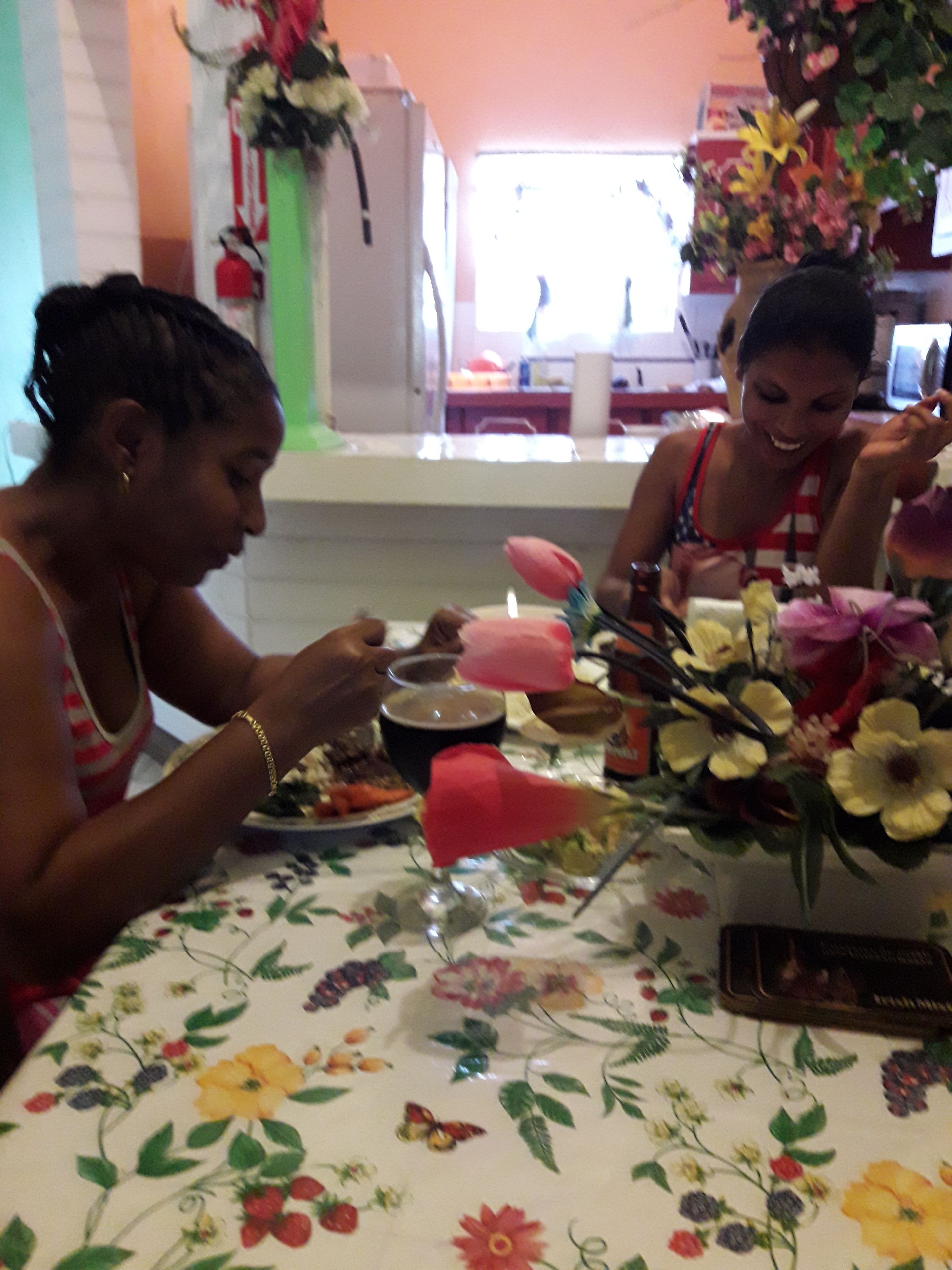 A dining table with a floral tablecloth, a vase with flowers, and a candle.