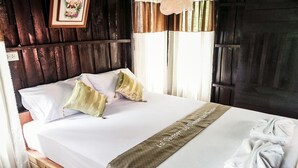 Una cama bien hecha con una colcha blanca, dos almohadas y una toalla.