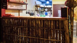 Un rústico espacio de bar con listones de madera, luces colgantes y utensilios de cocina.