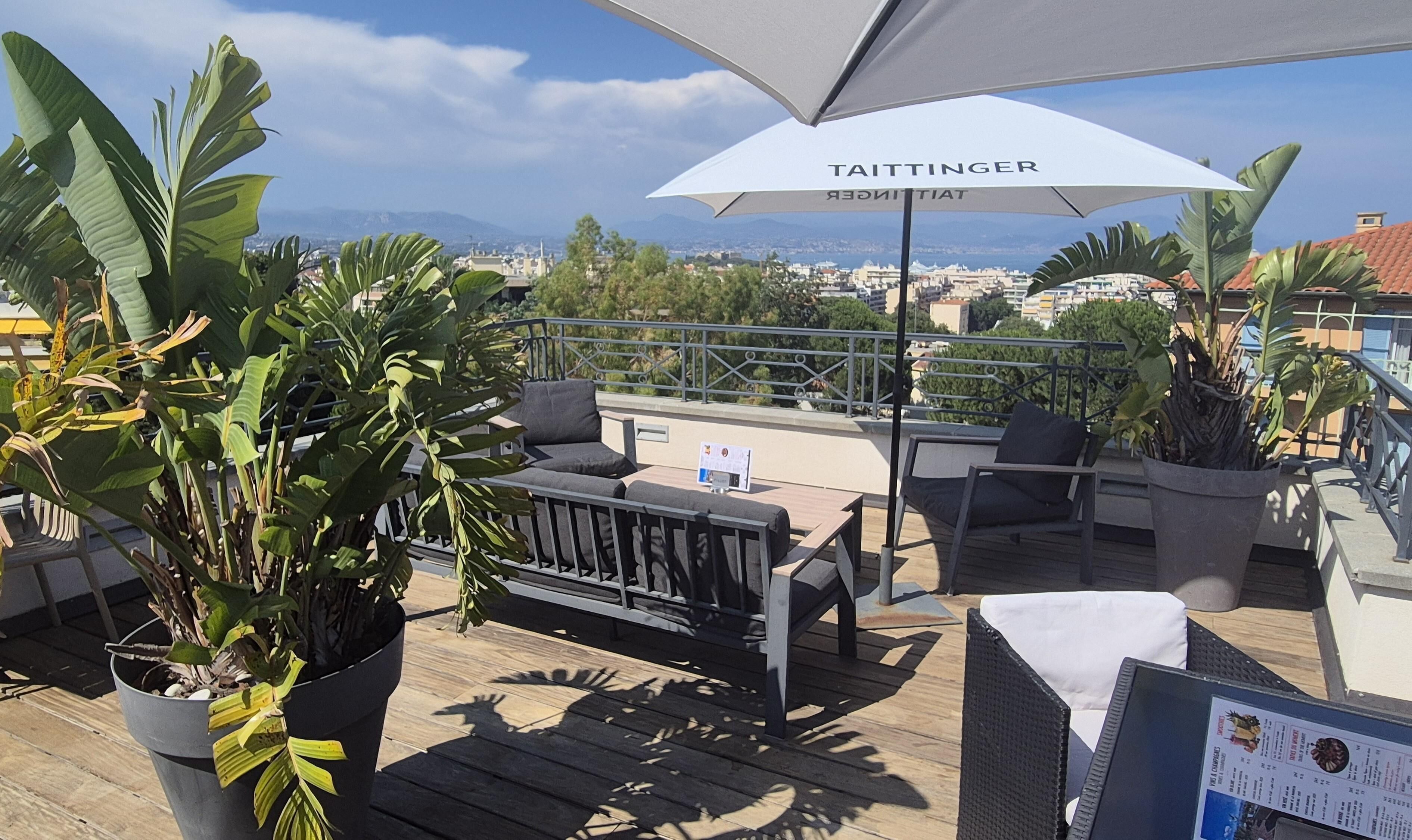 Une terrasse sur le toit, avec des sièges en plein air, un grand parasol et une vue sur le paysage urbain.