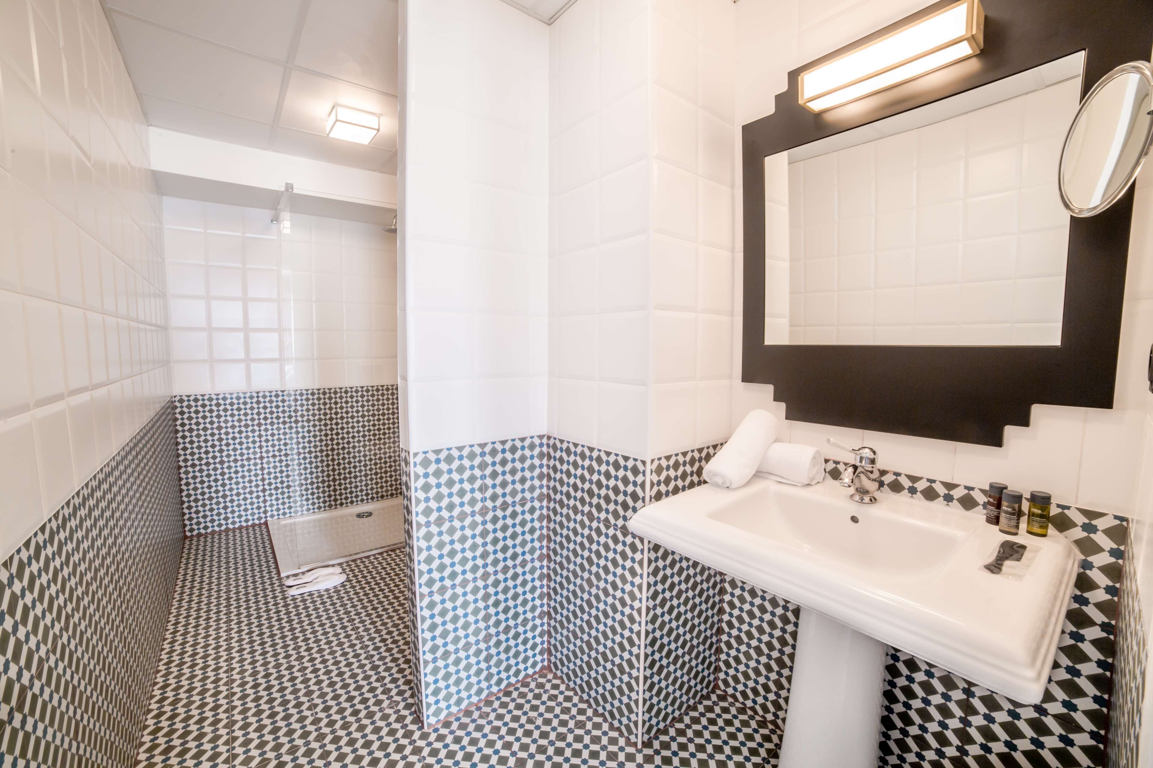 A bathroom with a checkered floor pattern, a white sink with a mirror above it, and a towel rack.