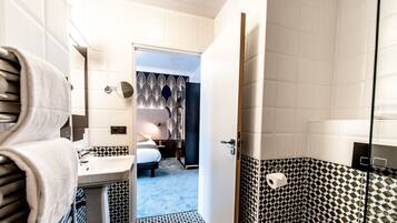 A hotel bathroom with a sink, toilet, and a shower area.