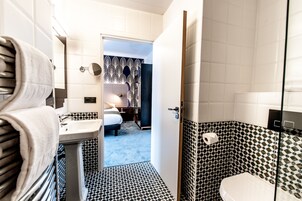 A hotel bathroom with a sink, toilet, and a shower area.