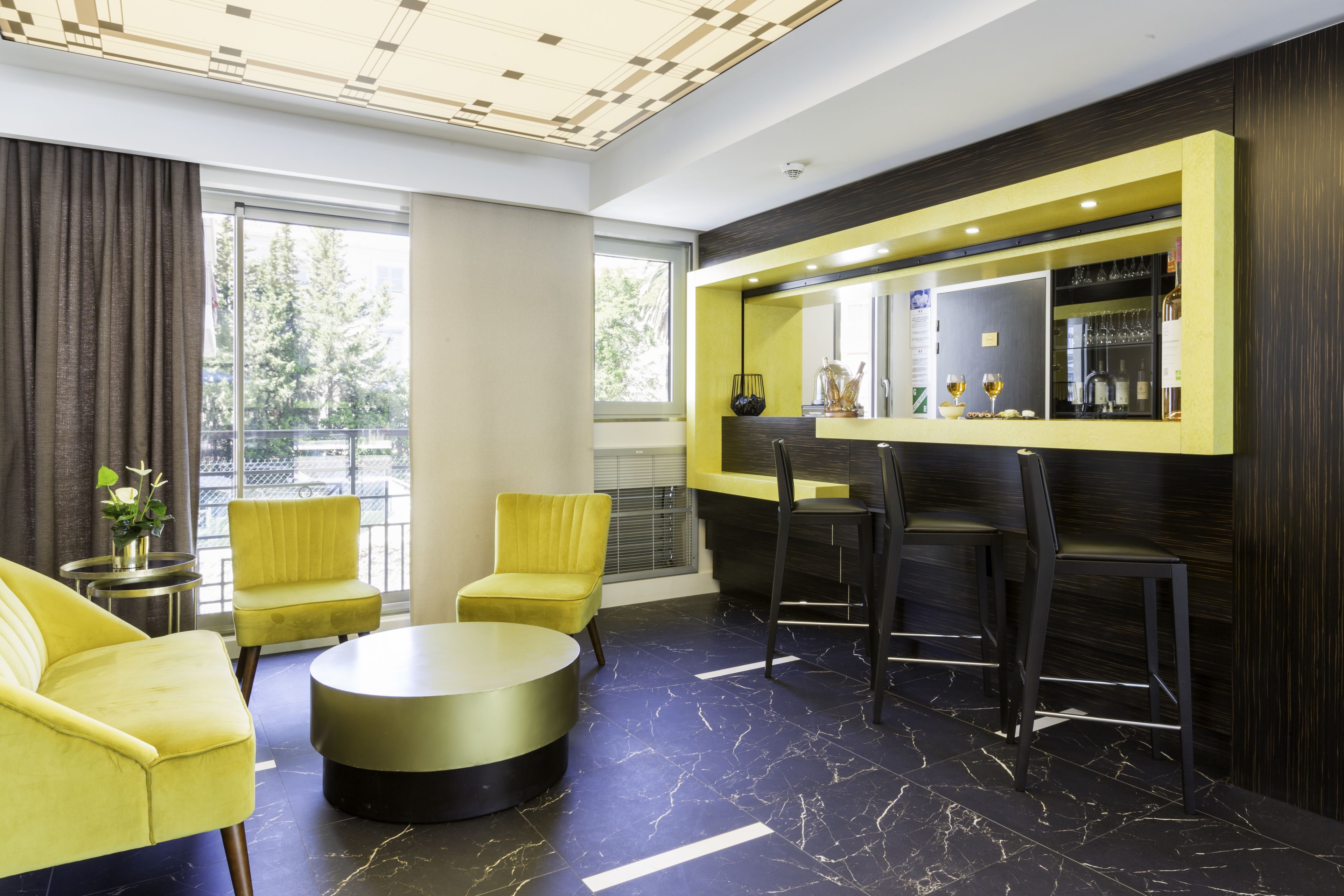 Un moderno vestíbulo de hotel con zona de bar, asientos y grandes ventanales.
