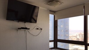 Habitación con un ventanal grande, un televisor de pantalla plana en la pared y un enchufe.