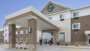 A hotel with a modern design, featuring a prominent 'G' logo on the facade, a covered entrance, and a brick accent wall. - GrandStay Cannon Falls (Cannon Falls)