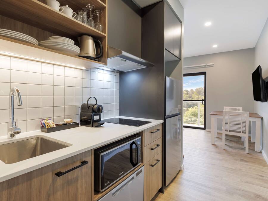 A modern kitchen with stainless steel appliances, a built-in oven, and a large window offering a view of the outdoors.