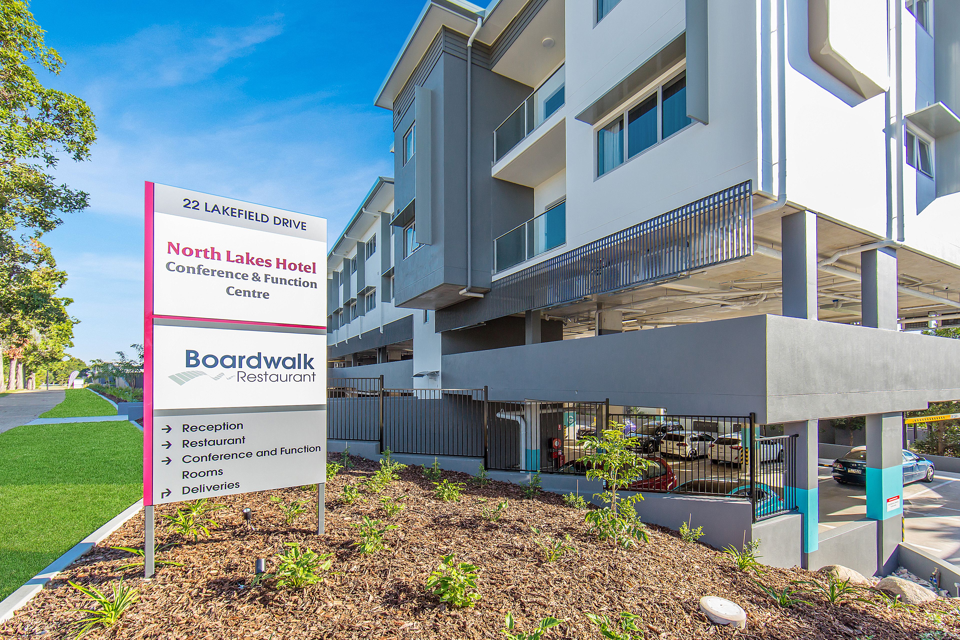 A modern hotel with a sign indicating amenities such as a restaurant, conference center, and rooms.