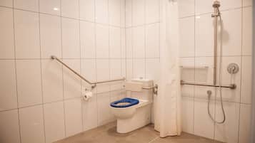 Ein Badezimmer mit Toilette, Dusche und Haltegriffen.