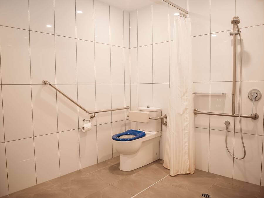 Ein Badezimmer mit Toilette, Dusche und Haltegriffen.