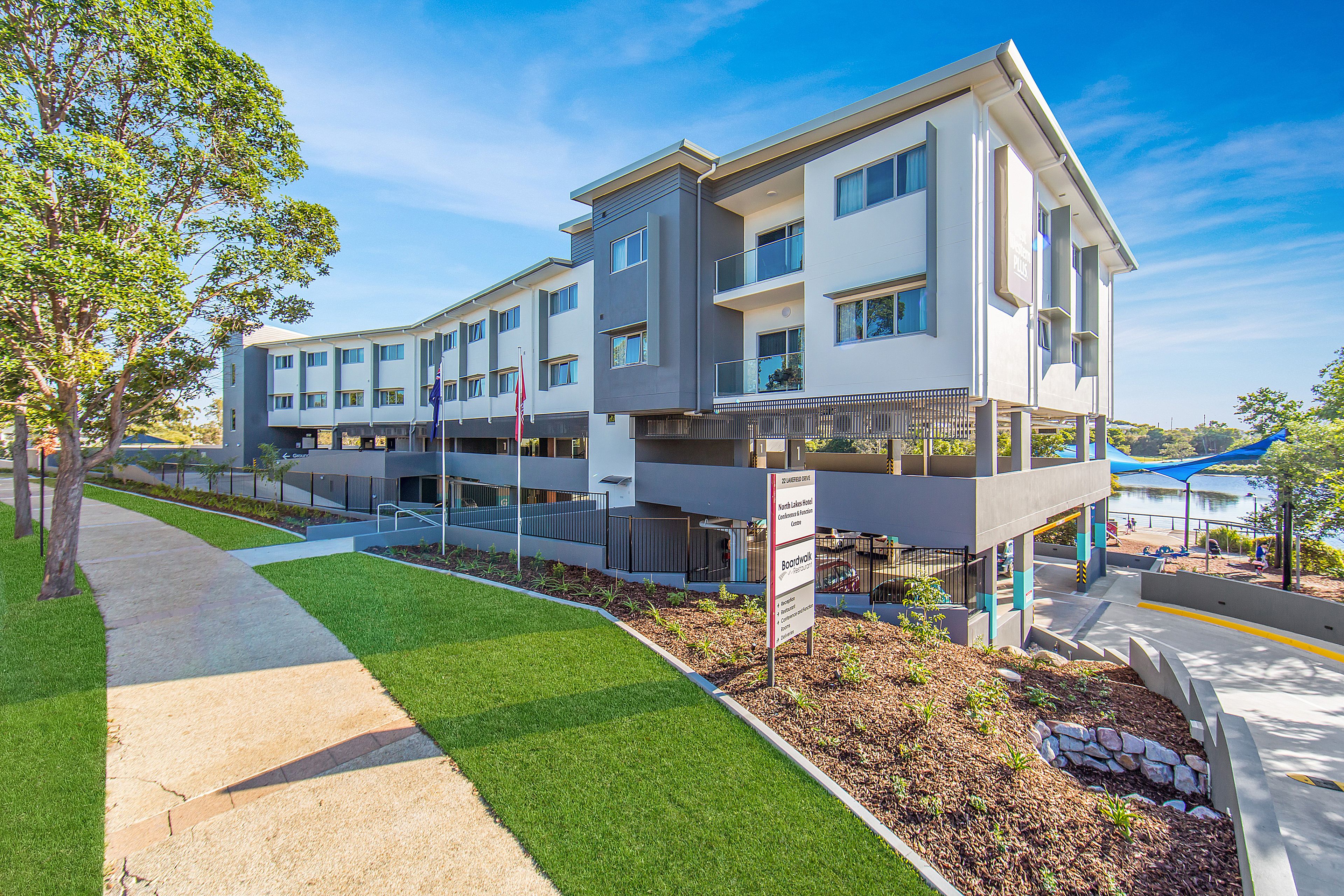 A modern multi-story building with a flat roof, large windows, and a balcony.