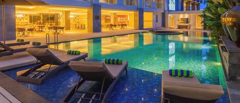 Una piscina al aire libre, sillones reclinables de piscina