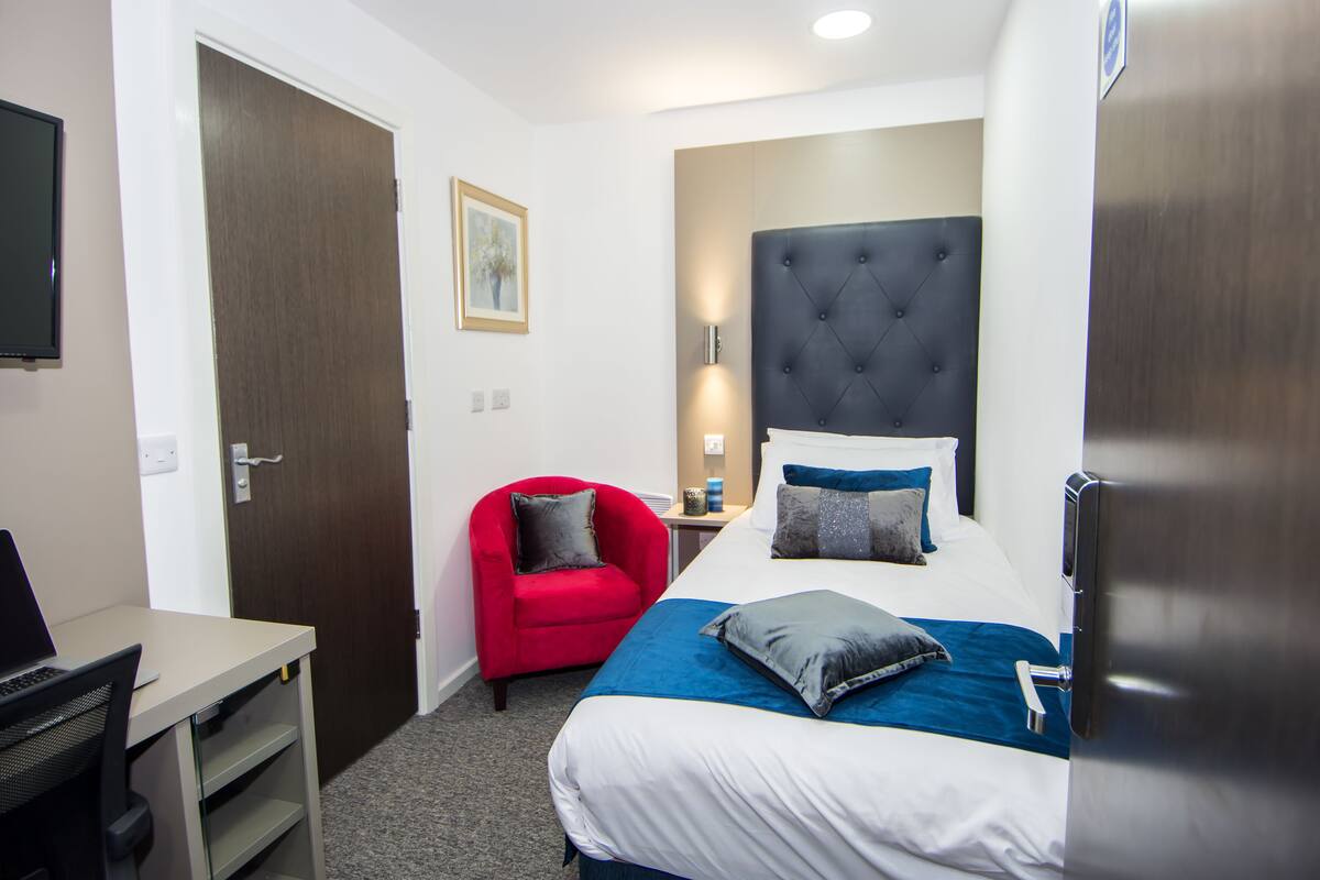Ein Hotelzimmer mit Bett, Schreibtisch, Stuhl und Fernseher.