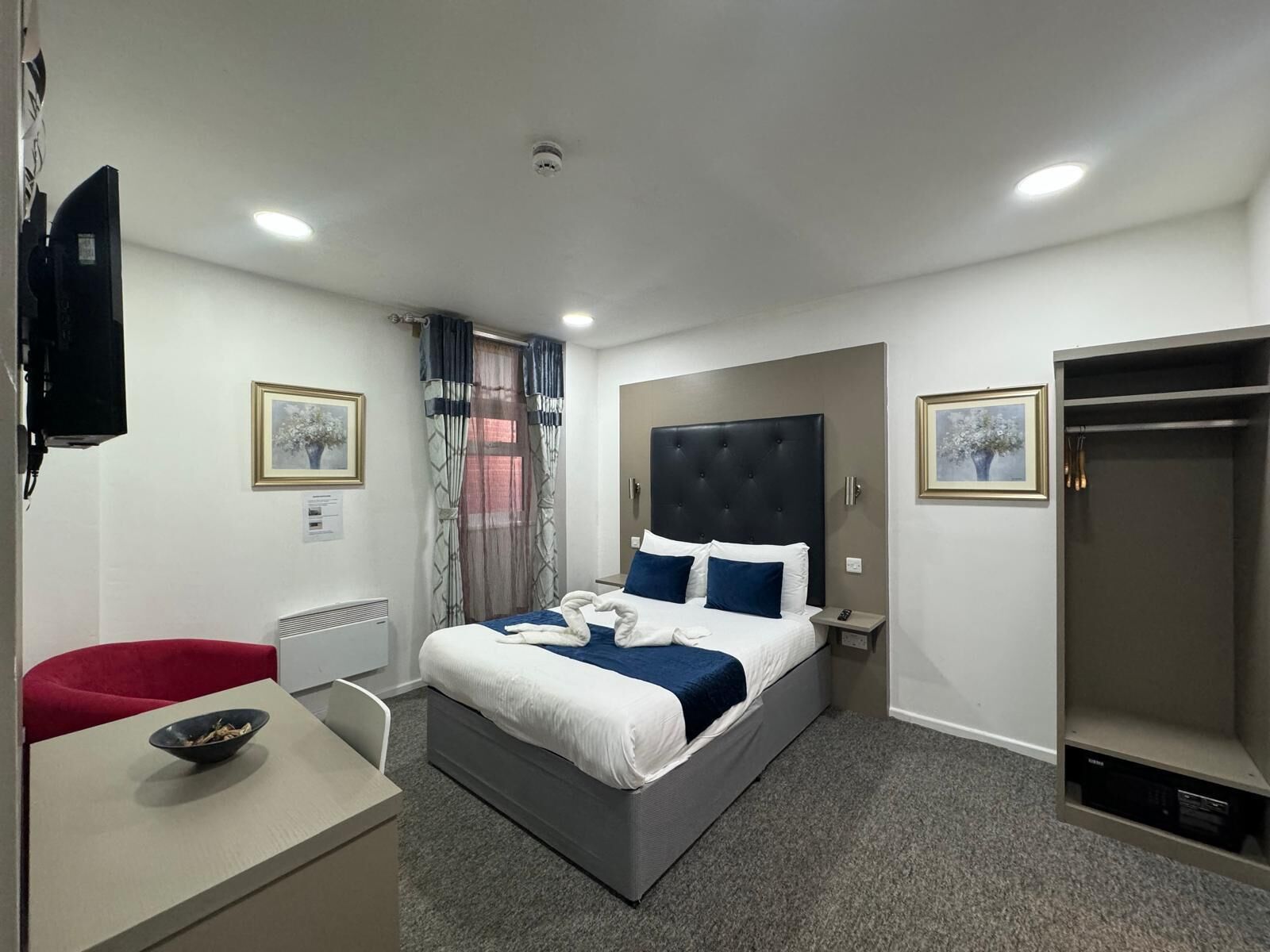 Una habitación de hotel con cama, escritorio, silla, armario y televisor.