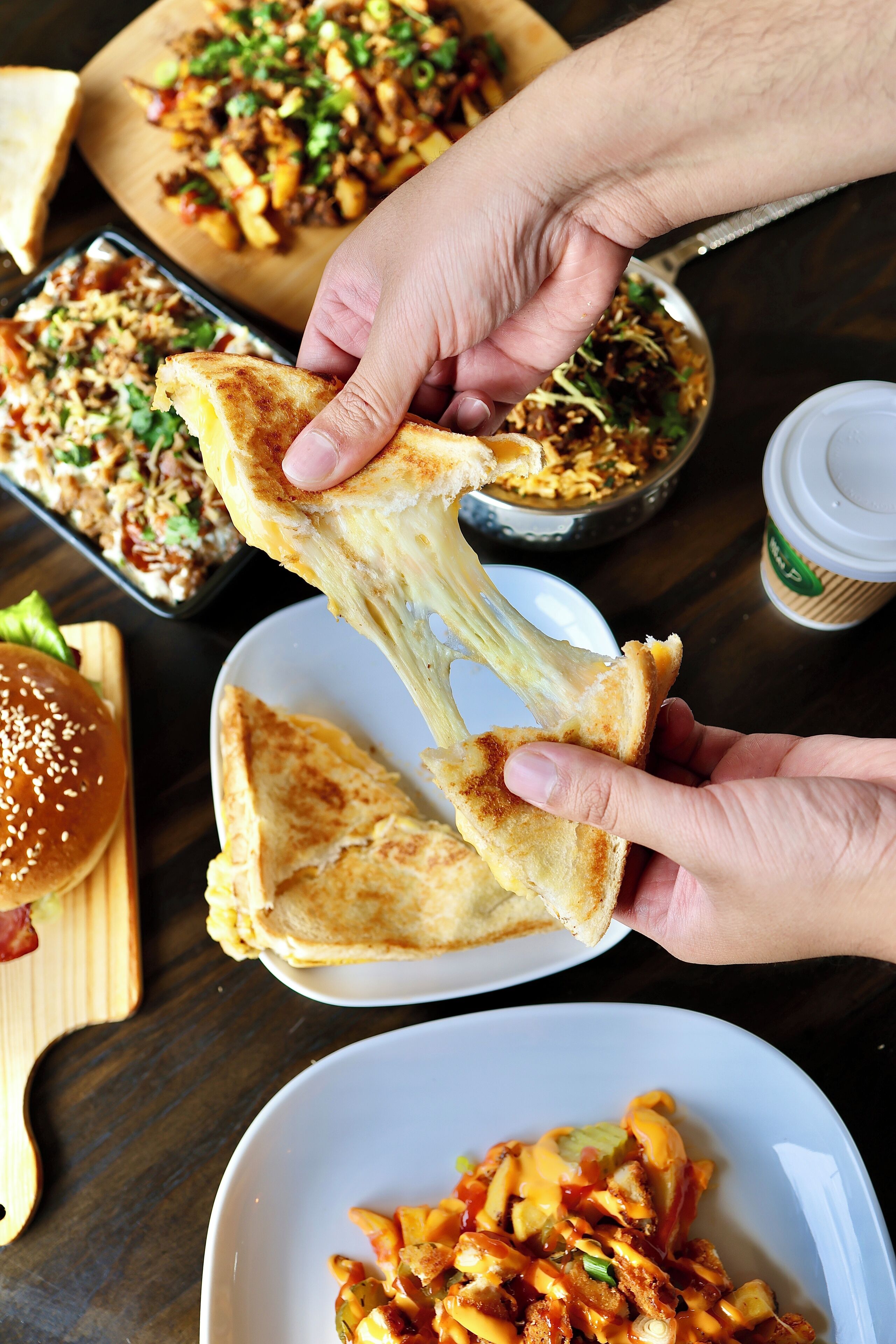 A person holding a piece of grilled cheese sandwich.