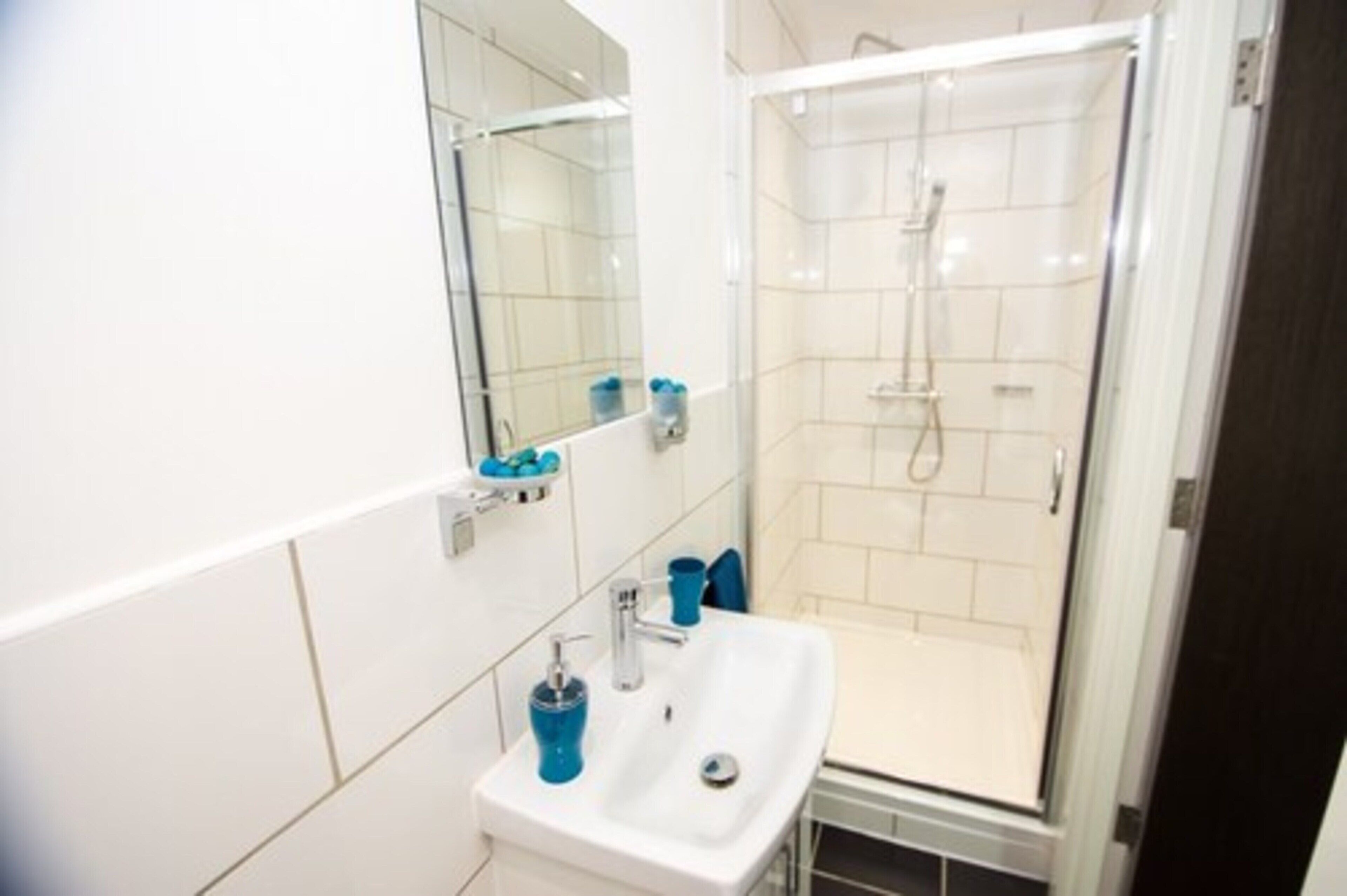 Une salle de bain moderne avec un lavabo blanc, un miroir et une douche à parois de verre.