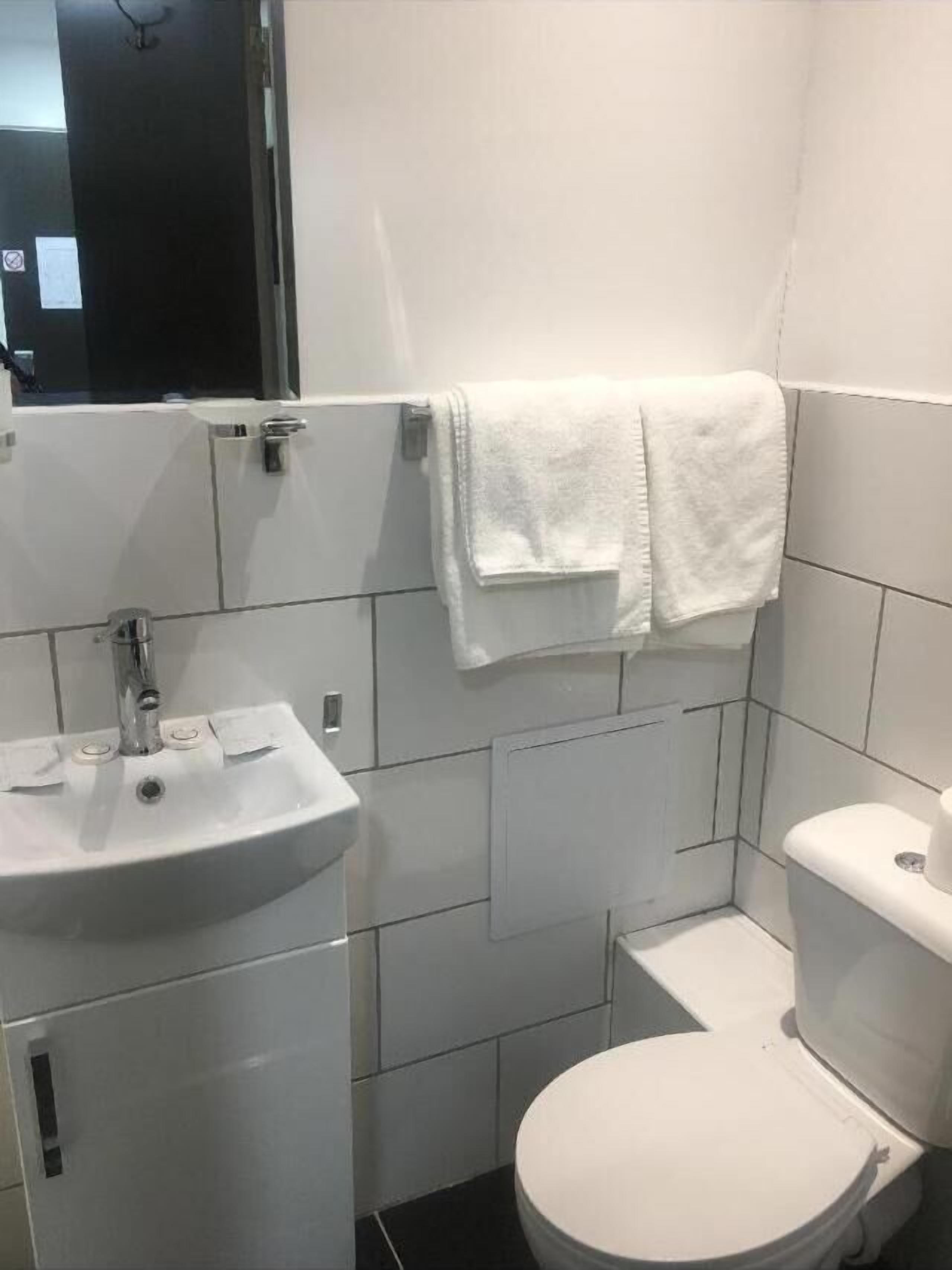 Un baño pequeño y moderno con un lavamanos, inodoro y perchero blanco.
