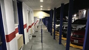 Un espace de stationnement couvert, avec des rangées de voitures garées et une allée centrale.