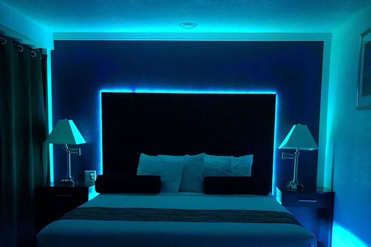 A large bed with a headboard, two bedside tables with lamps, a bench, and a patterned carpet.