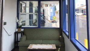 Une pièce dotée d’un ventilateur de plafond, d’un canapé, d’une petite table et de grandes fenêtres donnant sur la rue.