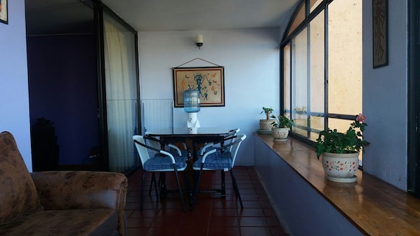 Un coin repas avec une table et des chaises, un distributeur d’eau et des plantes en pot sur un balcon offrant une vue agréable.