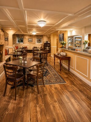 A spacious dining area with a high ceiling, chandeliers, and a buffet counter with various food items. - Bellevue Manor (Newport)