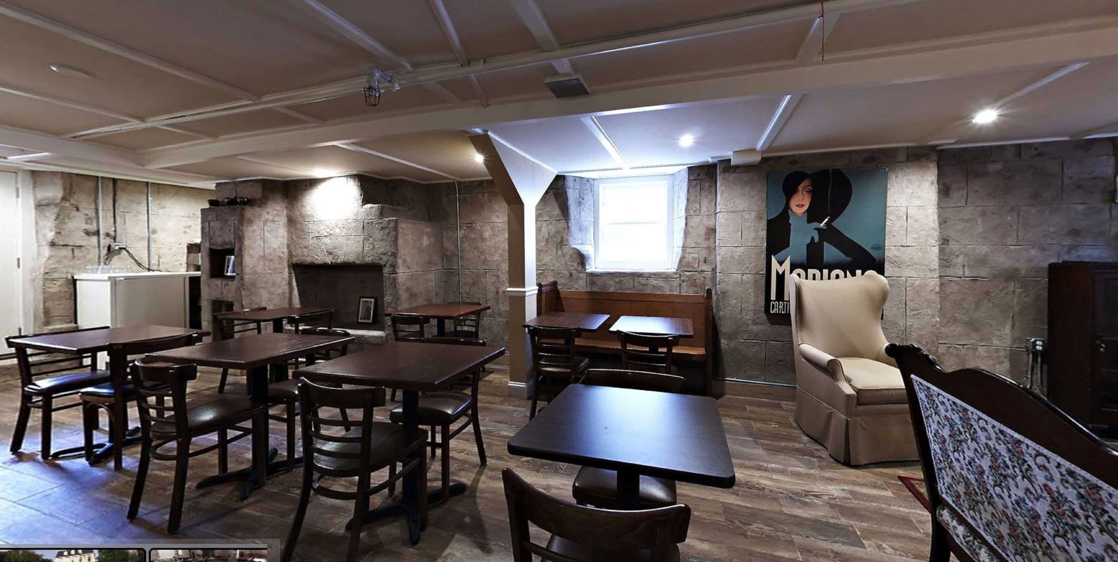 A restaurant with wooden tables and chairs, a stone fireplace, and a mural on the wall.