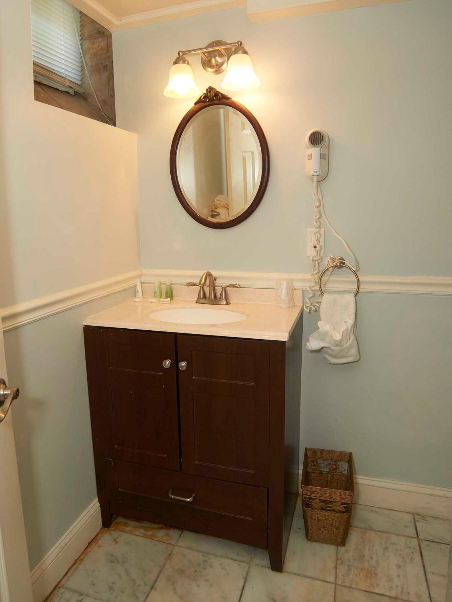 Un baño con tocador, lavamanos, espejo y toallero.
