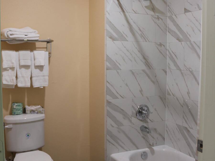 A bathroom with a toilet, a shower with a glass door, and a towel rack with folded towels.