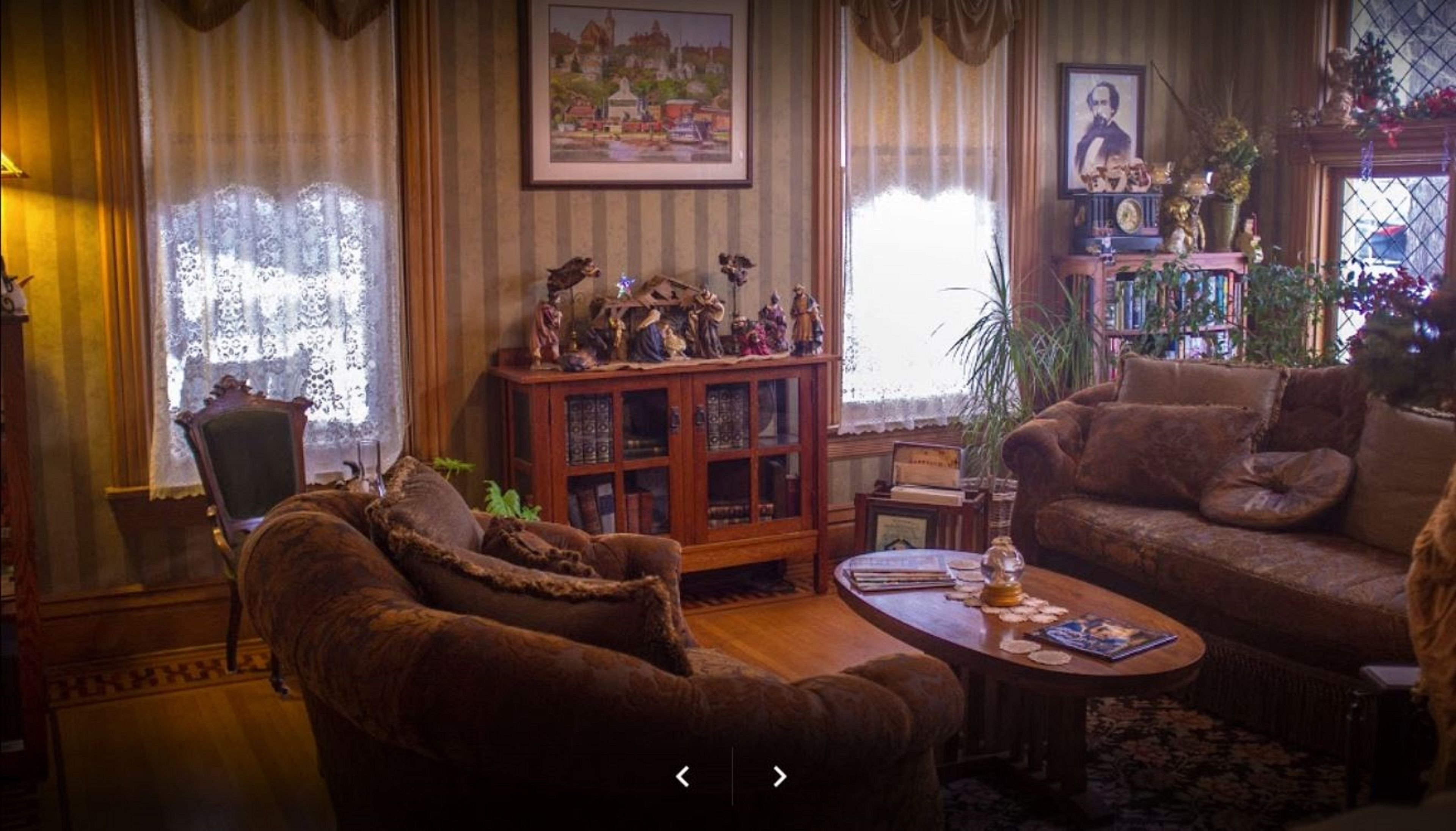 A cozy living room with a brown sofa, a wooden cabinet with glass doors, and a framed picture on the wall.