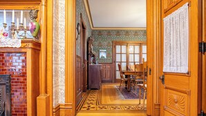Een hal met een houten vloer, een metselstenen open haard en een eethoek met een tafel en stoelen.